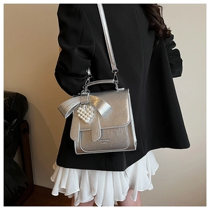 Detail of silver metallic bag with large bow, heart pearl charm, and crushed texture