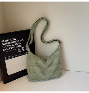 Detail of light mint green canvas tote with distressed fringe texture and silver zipper