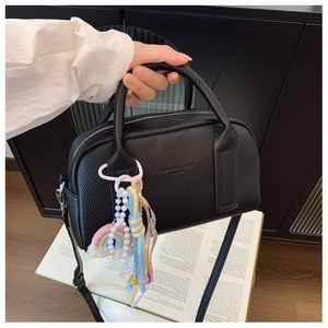 Detail of black lychee grain leather mini handbag with colorful decorative charms