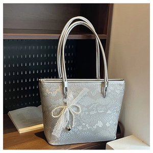 Detailed close-up of silver tote bag with snakeskin texture and pearl bow decoration