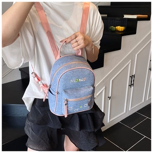 Detail of light blue denim backpack featuring pink contrast straps and MLBAOB embroidery