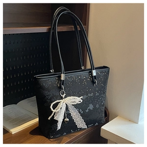 Detail of black snake embossed tote bag with white lace pearl butterfly bow charm