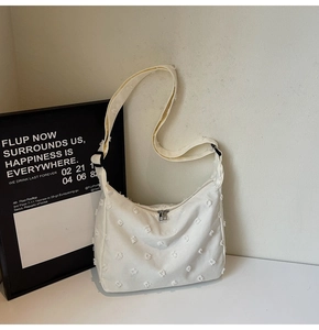 Detail of white canvas tote bag showing the unique textured tassel fabric and zipper closure