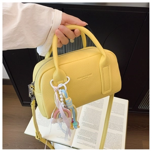 Detail of yellow lychee leather bowling bag with cute rainbow and tassel charms