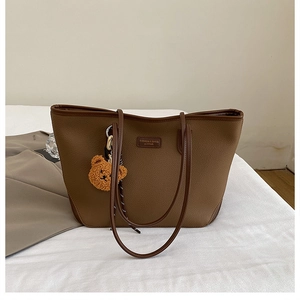 Dettaglio della borsa tote in pelle marrone con un simpatico ciondolo a forma di orso