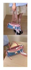 Detail of denim baguette bag with red gingham patterns, lace trim and cherry embroidery