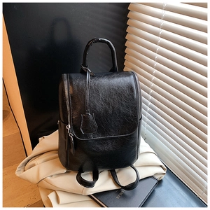 Detailed view of glossy black faux leather backpack texture with silver side zipper detail