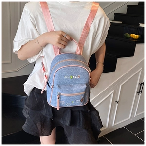 Detail view of denim backpack with pink straps and colorful heart embroidery