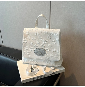 Detail des weißen Mode-Rucksacks mit 3D-Blumen-Jacquard und silberner Metall-Logoplakette