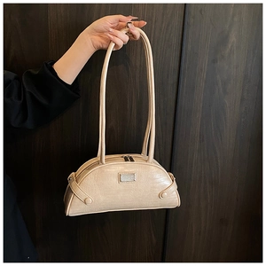 Detail of beige faux crocodile leather shoulder bag featuring silver metal brand plate