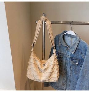 Detail of beige canvas tote bag featuring stylish fringe edges and adjustable wide strap