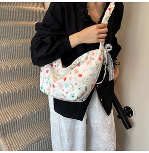 Detailed shot of white crescent crossbody bag with floral print and lace bow