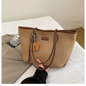 Dettaglio borsa tote kaki in pelle a grana di litchi con ciondolo orsetto marrone