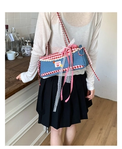 Detail of blue denim baguette bag with lace trim and red checkered bow decoration
