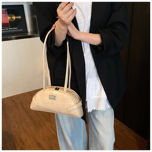 Close-up of cream crocodile pattern shoulder bag with metallic logo and zipper detail