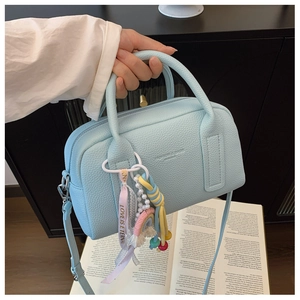 Close-up of light blue litchi grain faux leather bag with rainbow charm and pearl tassel