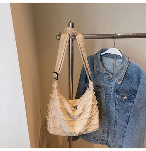 Close-up of beige canvas tote bag with fringe edge details and adjustable strap