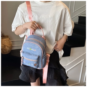 Detail of light blue denim mini backpack with pink leather trim and cute bear embroidery