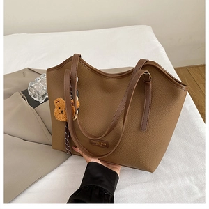 Detail of caramel brown tote bag with lychee texture and cute plush bear charm