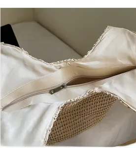 Detailed macro view of the smooth bronze zipper closure and beige fabric lining of straw bag