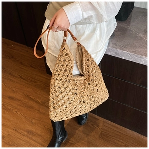 Detail of woven straw tote bag featuring hollow mesh pattern and brown leather shoulder strap