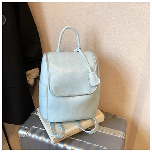 Close-up of light blue leather backpack with dual zippers on a metallic suitcase