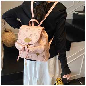 Pink printed leather mini bucket bag with gold hardware shown on a model in a minimalist room