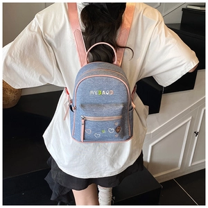 Mini denim backpack with pink straps and embroidery shown on model for size and fit