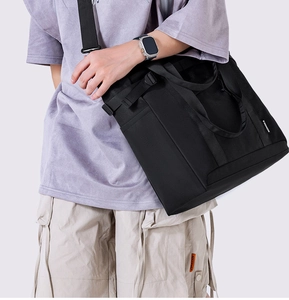 Side view of large black nylon tote bag worn as a crossbody with wide shoulder strap