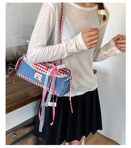 Detail of sweet lace trim and cherry embroidery on blue denim and red plaid handbag