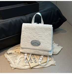 Detailaufnahme von weißem 3D-Floral-Jacquard-Stoff und silberner Metallschnalle am Rucksack