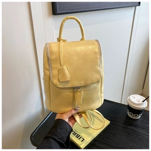 Detailed texture of yellow faux leather backpack with top handle and tassel charm