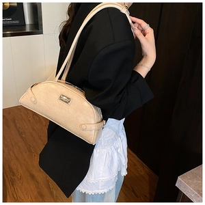 Detail of cream crocodile embossed leather shoulder bag with metallic logo plate