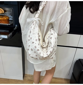 Detail of floral Oxford shoulder bag with ruffled strap and lace bow accent