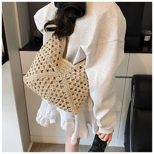 Detailed back view of a beige hand-woven crochet tote bag on a fashion model