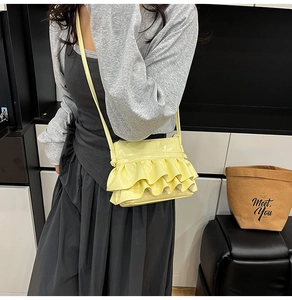 Detail of light yellow ballet style crossbody bag with three-tier ruffle pleats
