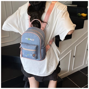 Detailed back view of mini denim backpack with pink straps and cute embroidery