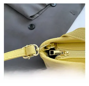 Detail of yellow lychee leather handbag showing golden zipper and metal strap buckle