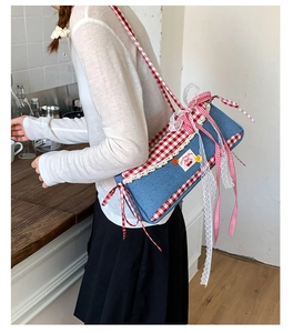 Detailed close-up of blue denim baguette bag with lace trim and cherry embroidery