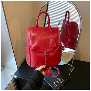 Detailed view of a red leather backpack showing texture and sturdy carrying handle