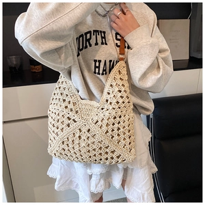 Detail of beige crochet hobo bag with hollow geometric patterns and brown leather strap