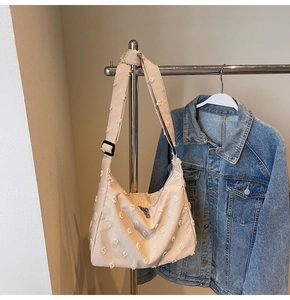 Close-up of beige canvas tote bag with textured fringe details and wide shoulder strap