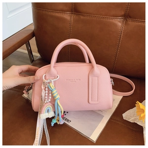 Detail of pink lychee leather Boston bag with fashion logo and rainbow pendant charm