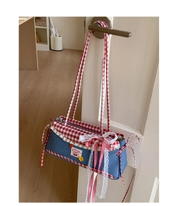 Detail of denim shoulder bag with red gingham bow, lace edges, and cherry embroidery