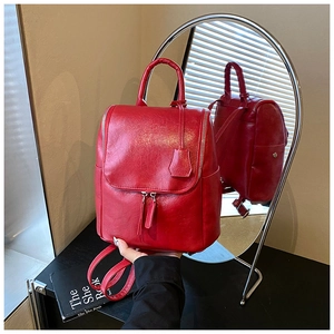 Detailed mirror reflection of a red glossy backpack showing straps and silver buckles