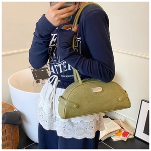 Detail of avocado green crocodile pattern shoulder bag on model in a cozy lifestyle setting