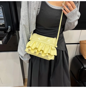 Detailed side view of a bright yellow crossbody bag with tiered ruffle pleat design