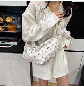 Floral oxford shoulder bag with pleated straps and lace bows shown on model in kitchen