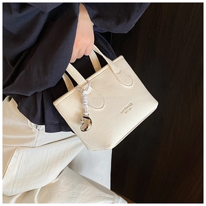 Dettaglio della mini borsa a secchiello bianco crema con trama litchi e ciondolo argento