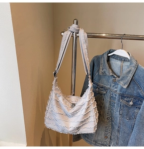 Detail of light blue denim tote with layered raw-edge stitching and adjustable strap